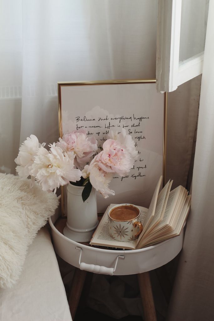 A serene bedside scene with coffee, pink peonies, and an open book for a cozy ambiance.